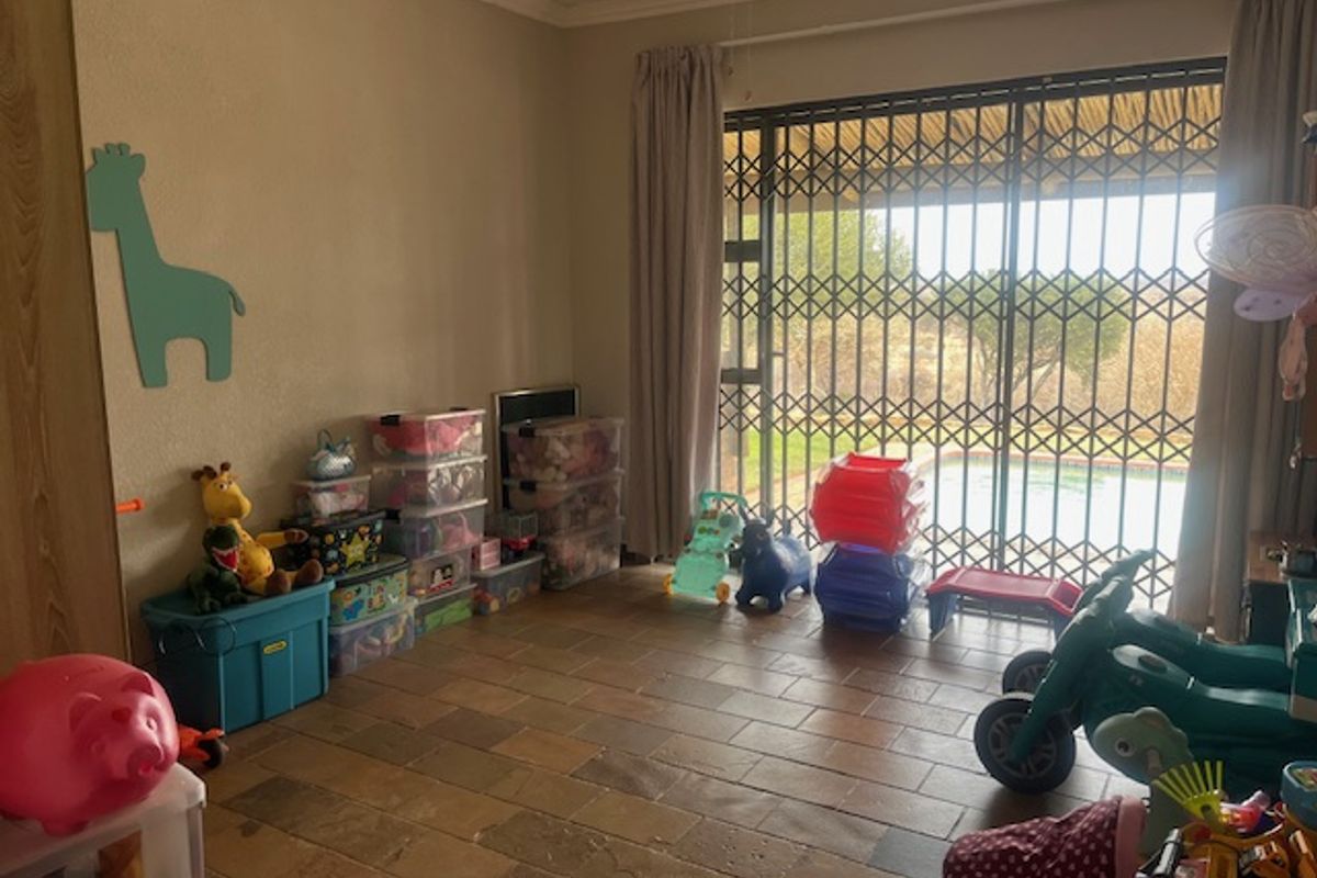Living room featuring stone tile flooring and a sliding glass door with security gate, providing direct access to the outdoor pool area.