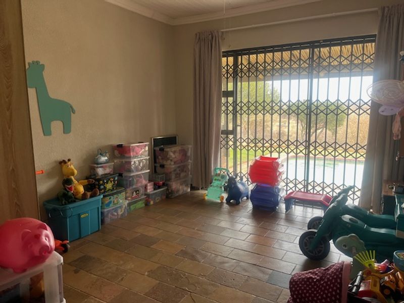 Living room featuring stone tile flooring and a sliding glass door with security gate, providing direct access to the outdoor pool area.