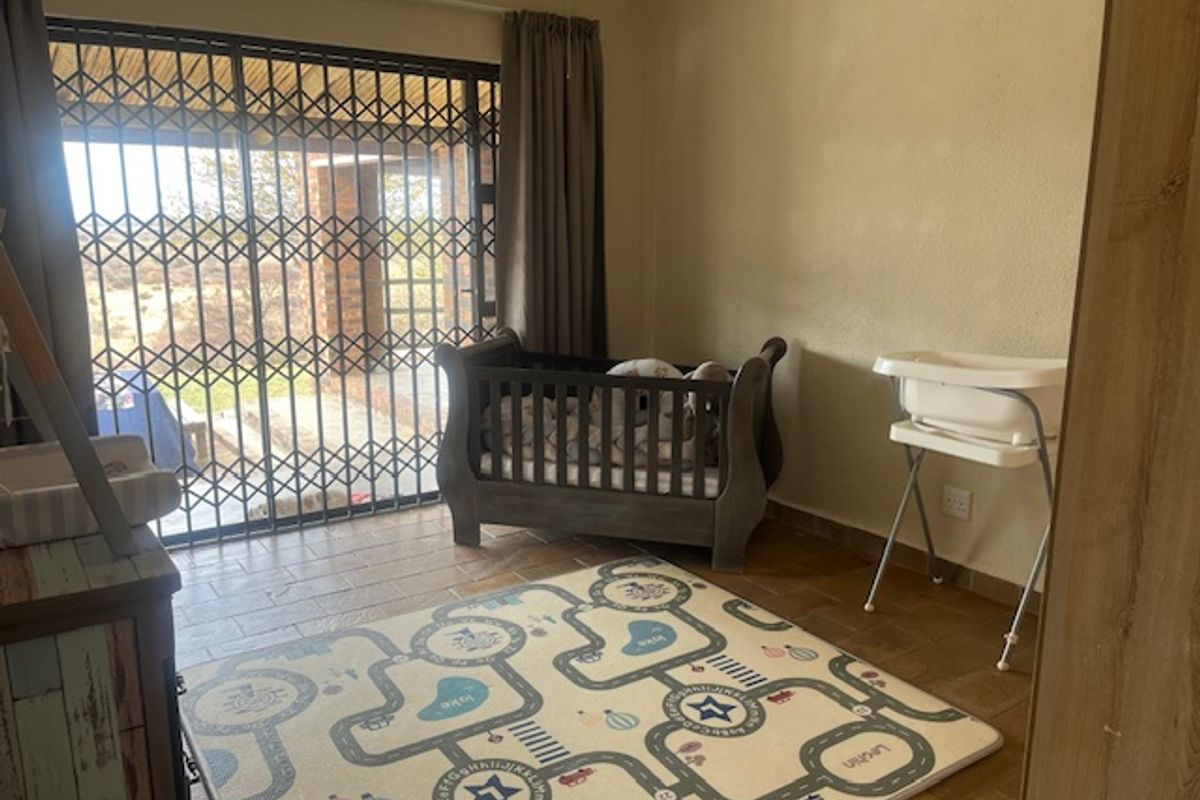 A bedroom featuring tiled flooring and a sliding glass door with a security gate, providing direct access to the outdoor area.