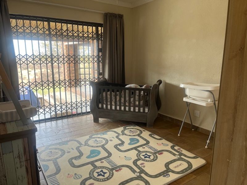 A bedroom featuring tiled flooring and a sliding glass door with a security gate, providing direct access to the outdoor area.