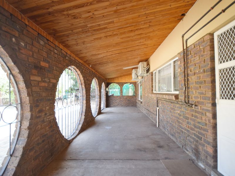 A covered patio area featuring distinctive circular brick openings with security grilles, timber ceiling, and concrete flooring, providing a functional outdoor transition space.