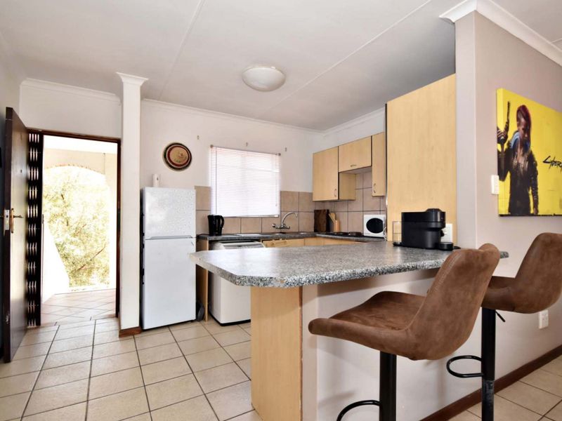 Open plan kitchen featuring a breakfast bar, granite countertops, and tiled flooring, with direct access to an outdoor patio area.