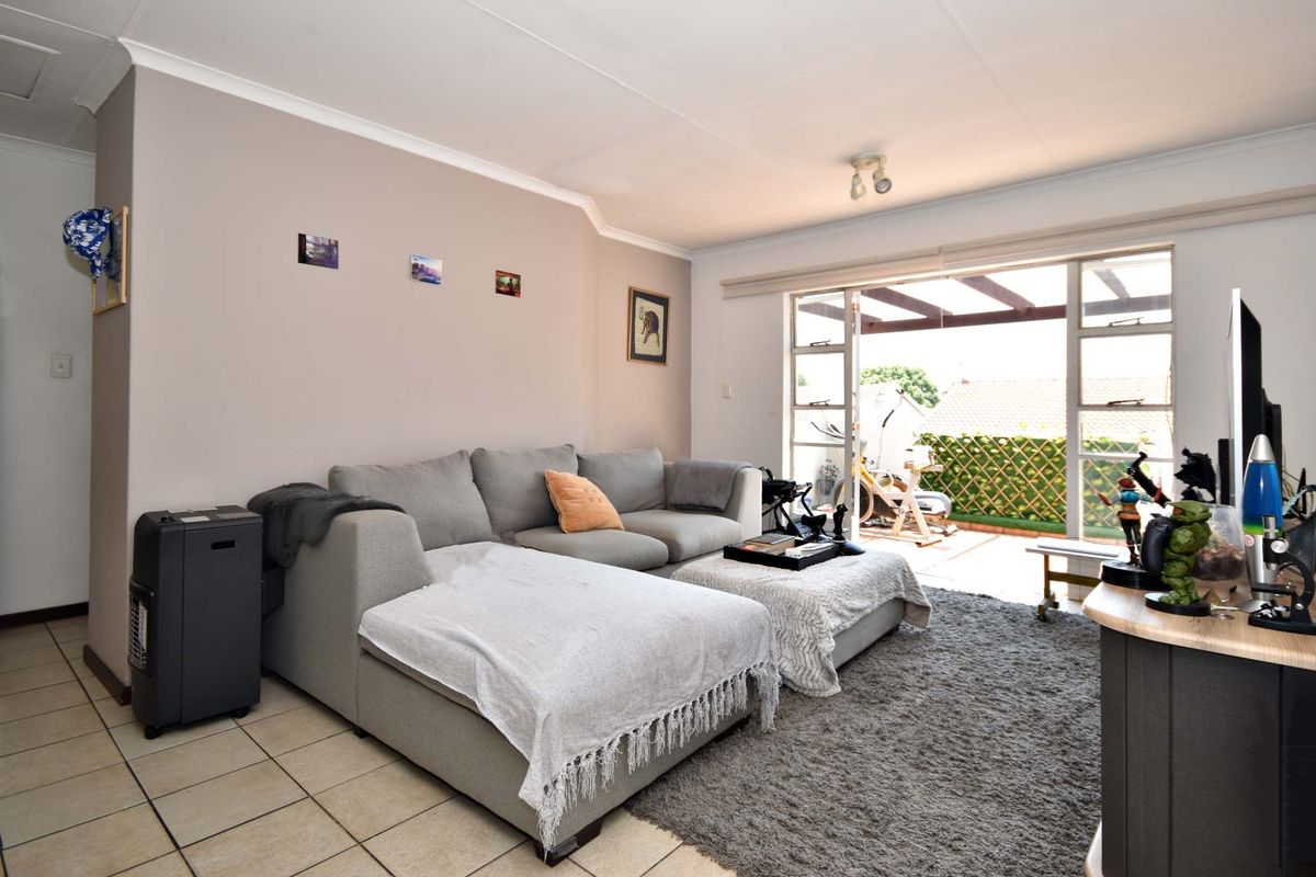 A comfortable living room featuring tiled flooring and large sliding glass doors that provide direct access to an outdoor patio area.