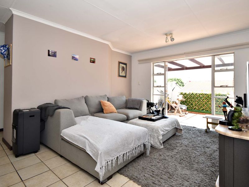A comfortable living room featuring tiled flooring and large sliding glass doors that provide direct access to an outdoor patio area.