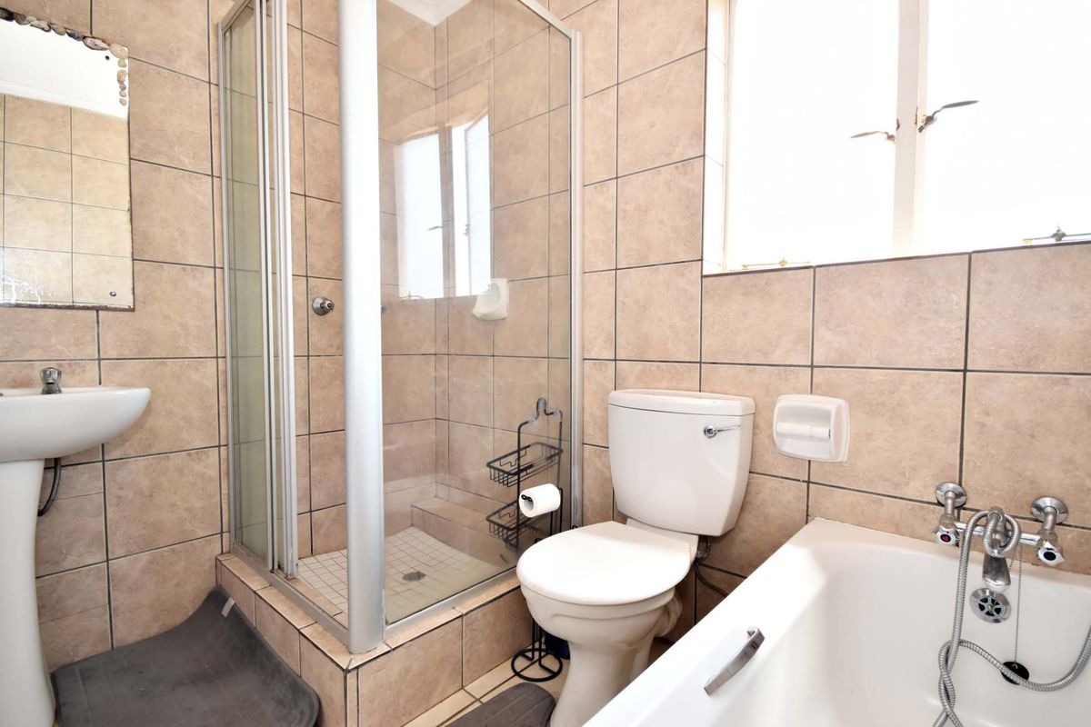A functional bathroom featuring a pedestal basin, a separate shower enclosure, a toilet, and a bathtub with tiled walls and flooring.
