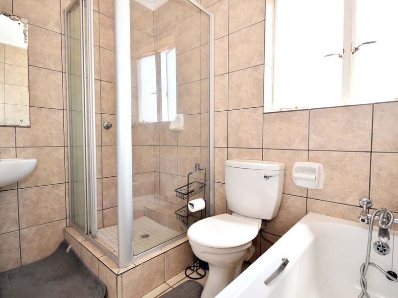 A functional bathroom featuring a pedestal basin, a separate shower enclosure, a toilet, and a bathtub with tiled walls and flooring.
