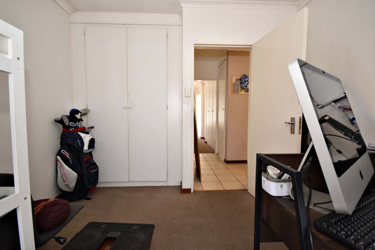 A bedroom featuring built-in cupboards, carpeted flooring, and a coved ceiling, with an open doorway leading to a tiled hallway.