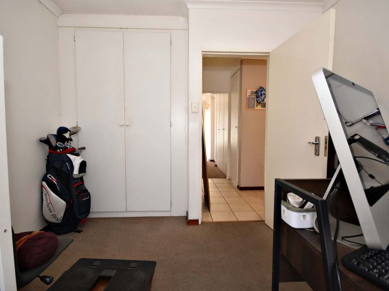 A bedroom featuring built-in cupboards, carpeted flooring, and a coved ceiling, with an open doorway leading to a tiled hallway.