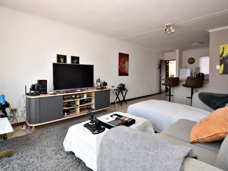 Open plan living area featuring tiled flooring and a breakfast bar connecting to the kitchen space.