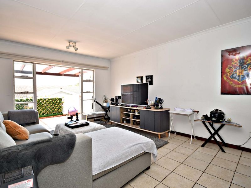 Spacious living room featuring tiled flooring and a large sliding glass door providing direct access to an outdoor patio area.