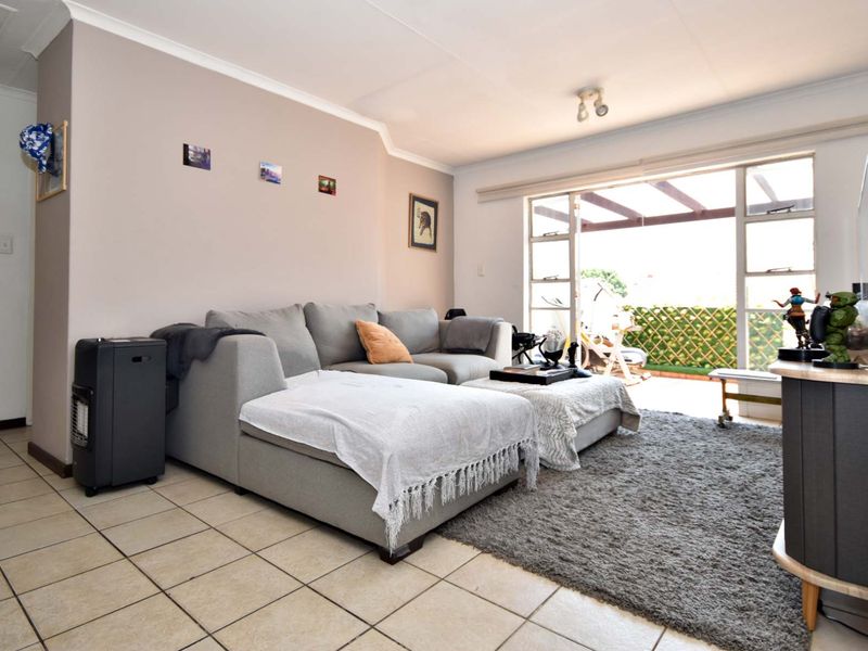 A living room featuring tiled flooring and a large sliding glass door providing access to an outdoor patio area.
