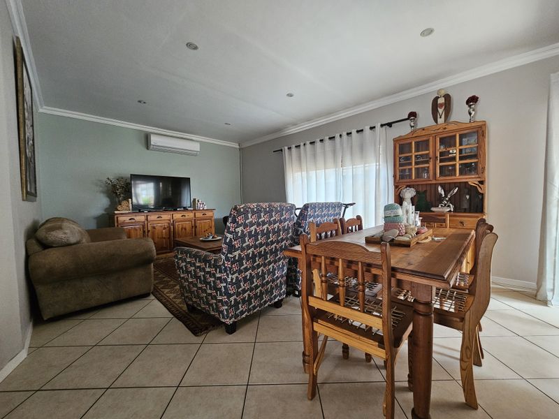 Open-plan living and dining area featuring tiled flooring, recessed downlighting, and a wall-mounted split-system air conditioner.