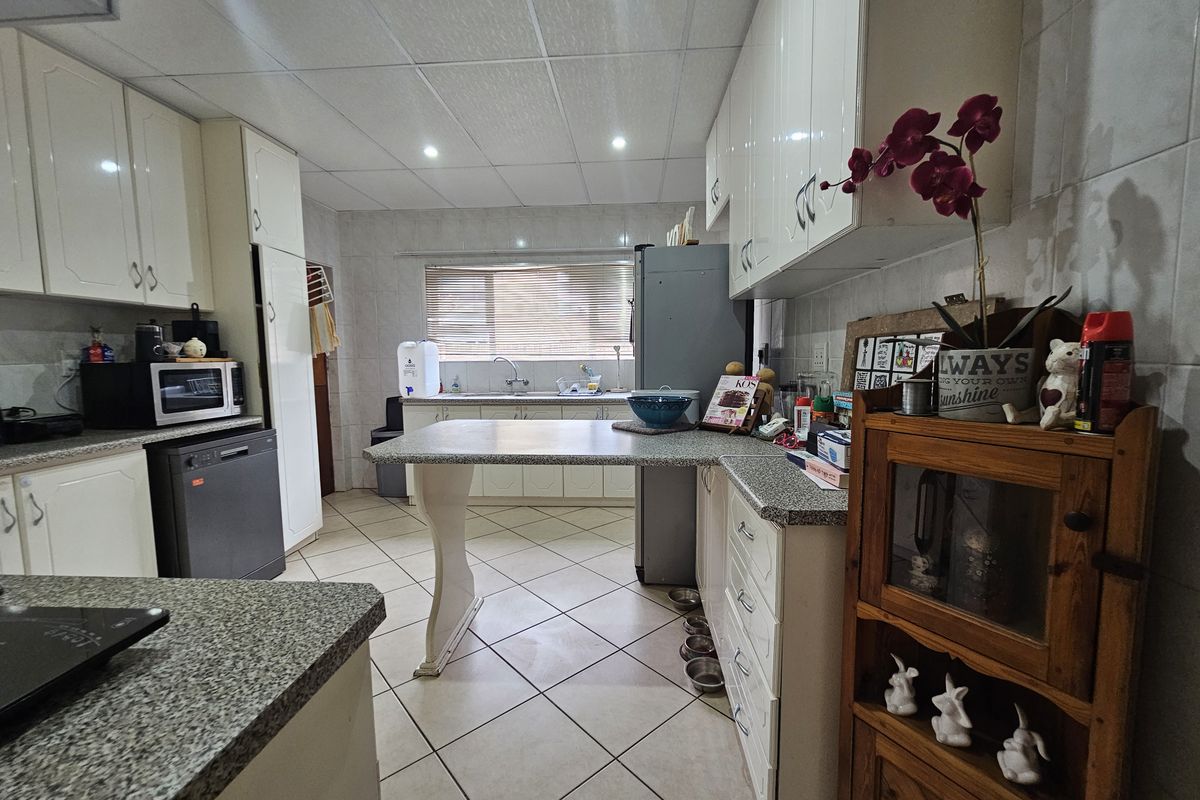 A functional kitchen featuring granite countertops, ample built-in cabinetry, tiled flooring, and a drop ceiling with recessed lighting.