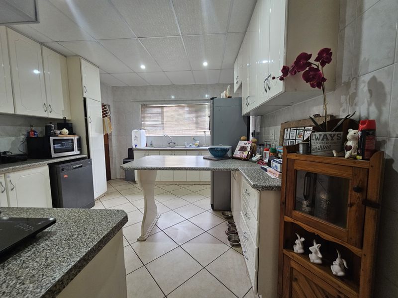 A functional kitchen featuring granite countertops, ample built-in cabinetry, tiled flooring, and a drop ceiling with recessed lighting.