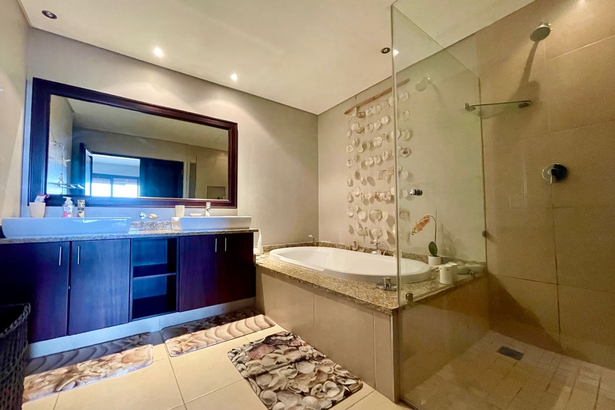 Modern bathroom featuring a double vanity with granite countertop, a built-in bathtub, and a glass-enclosed walk-in shower with tiled finishes.