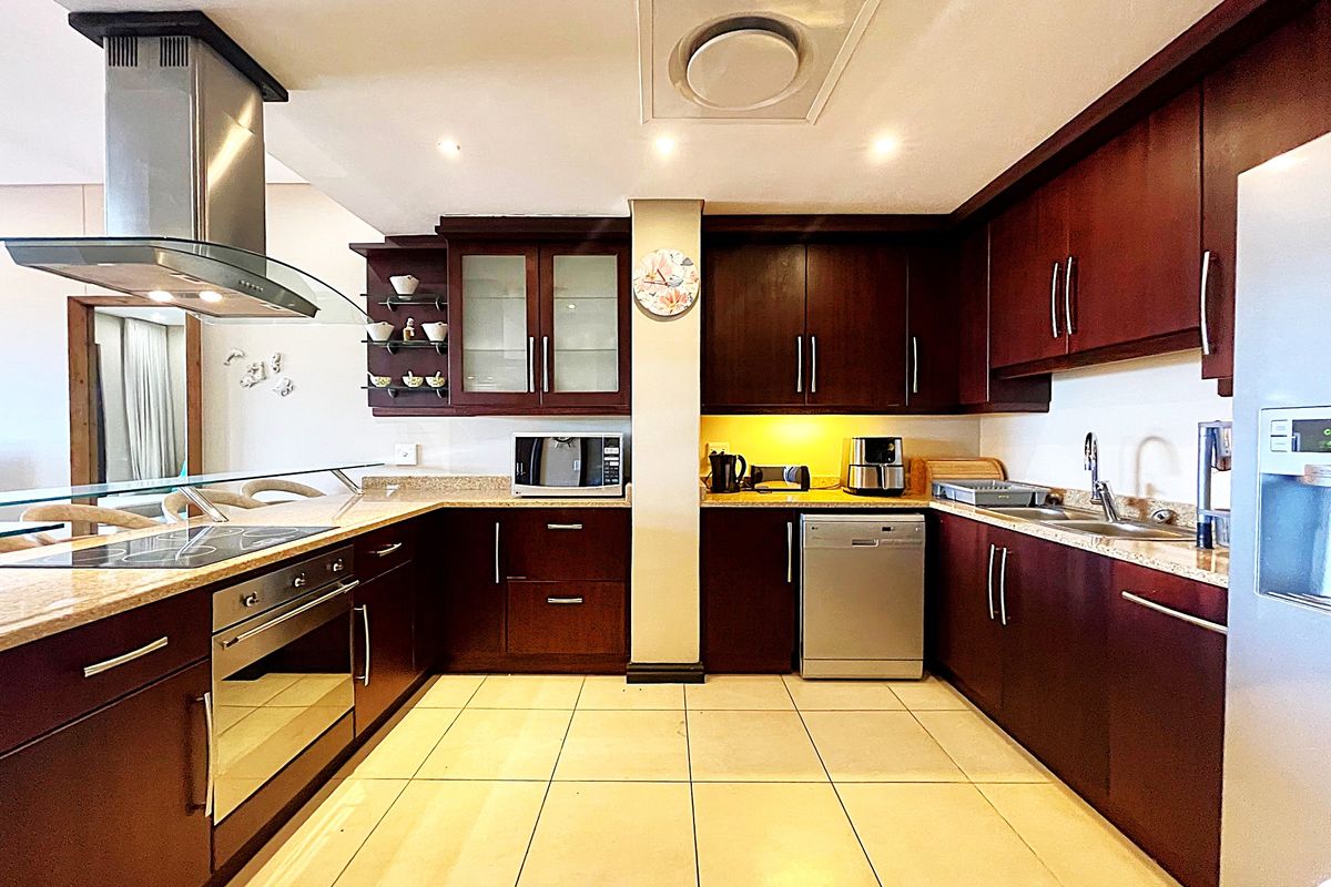 A functional kitchen featuring dark wood cabinetry, granite countertops, a built-in oven, stainless steel extractor fan, and tiled flooring.