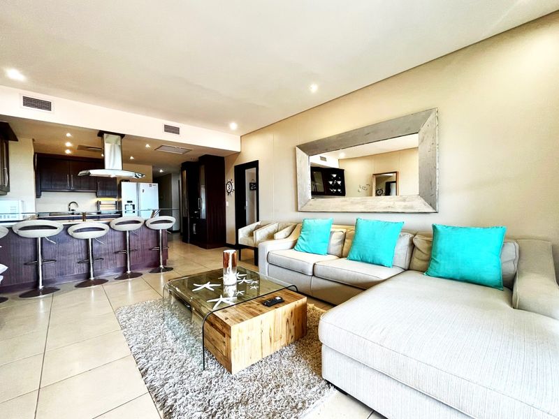 Open plan living area featuring a modern kitchen with breakfast bar, integrated cabinetry, and tiled flooring throughout.