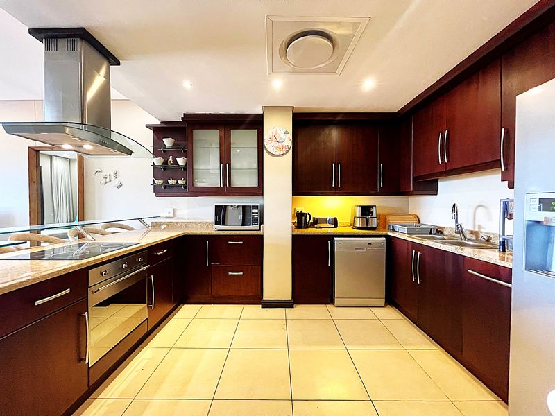 A functional kitchen featuring dark wood cabinetry, granite countertops, a built-in oven, stainless steel extractor fan, and tiled flooring.