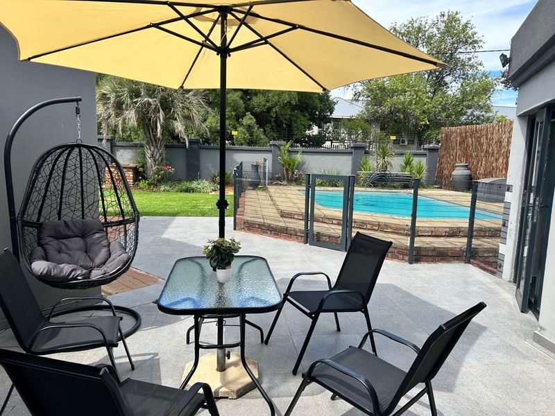 A paved outdoor patio area featuring a swimming pool with brick surround and secure perimeter walling, ideal for outdoor relaxation and entertainment.
