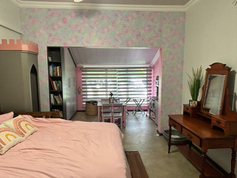 Spacious bedroom featuring built-in shelving, a sloped ceiling alcove, and modern roller blinds, offering a versatile layout with ample natural light.
