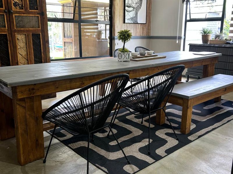 A modern dining area featuring polished concrete floors, an exposed brick feature wall, and timber slat accents, creating a contemporary industrial aesthetic.