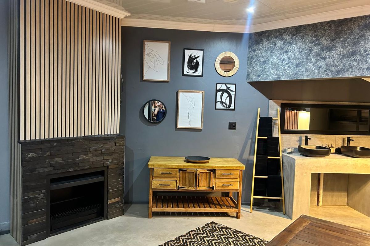 Modern living area featuring a stone-clad fireplace, timber slat feature wall, and a custom concrete vanity with dual vessel sinks.