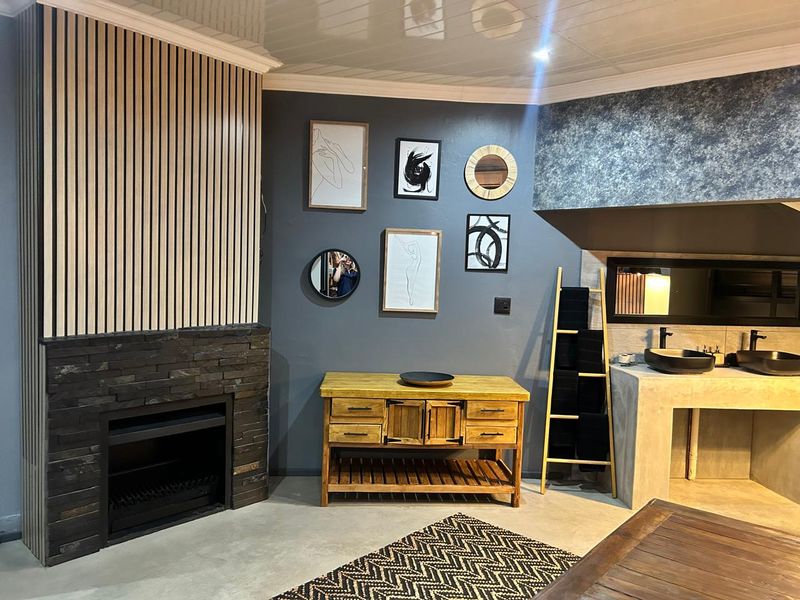 Modern living area featuring a stone-clad fireplace, timber slat feature wall, and a custom concrete vanity with dual vessel sinks.