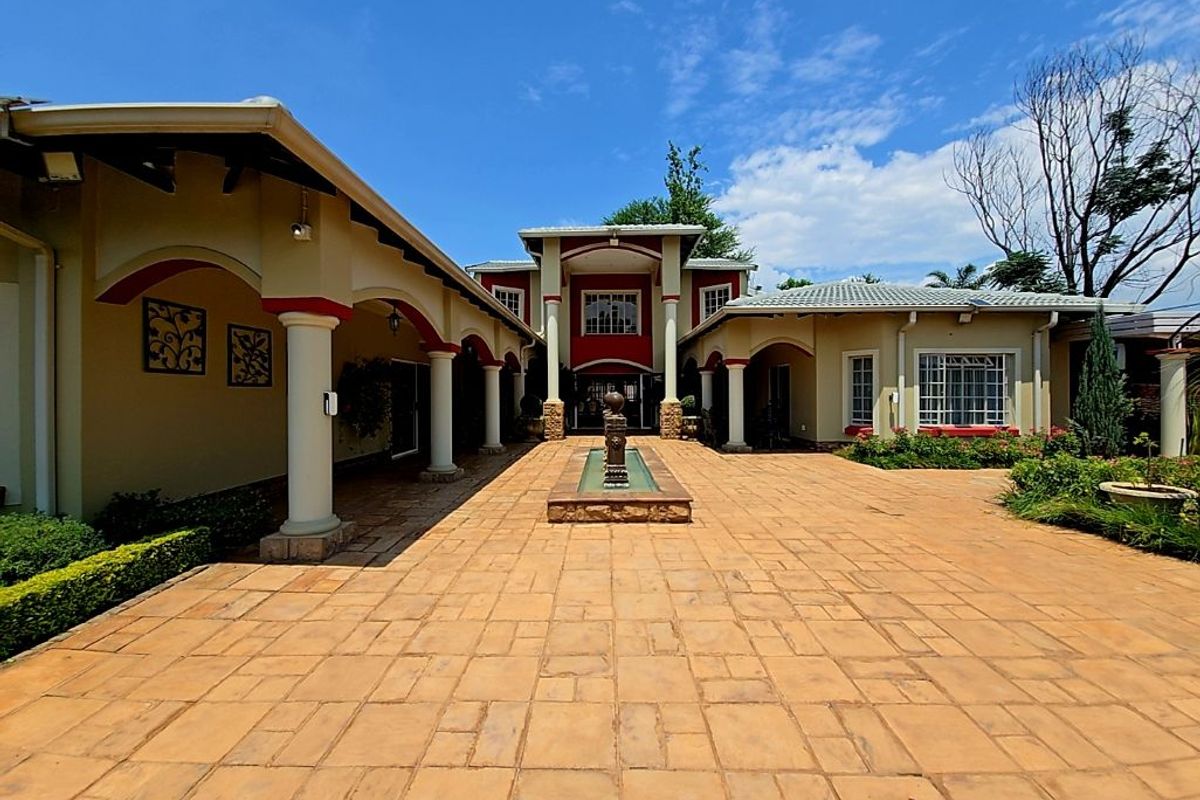 A spacious courtyard featuring paved flooring, a central water fountain, and covered walkways with architectural columns leading to the main entrance.