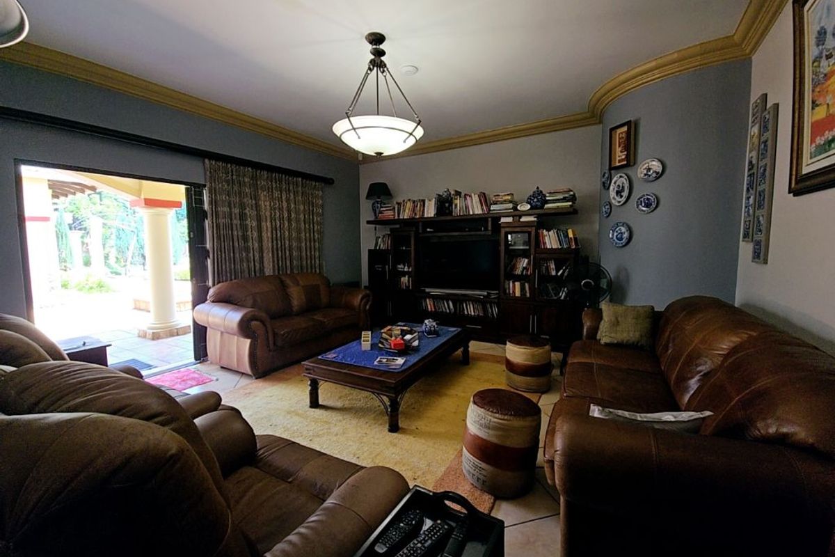A comfortable living room featuring built-in cabinetry, decorative crown molding, and large sliding glass doors providing direct access to the outdoor patio area.