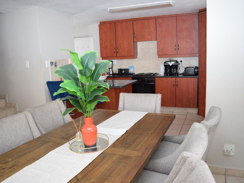 Open-plan dining area flowing into a functional kitchen featuring wood-finish cabinetry, granite countertops, and built-in cooking appliances.