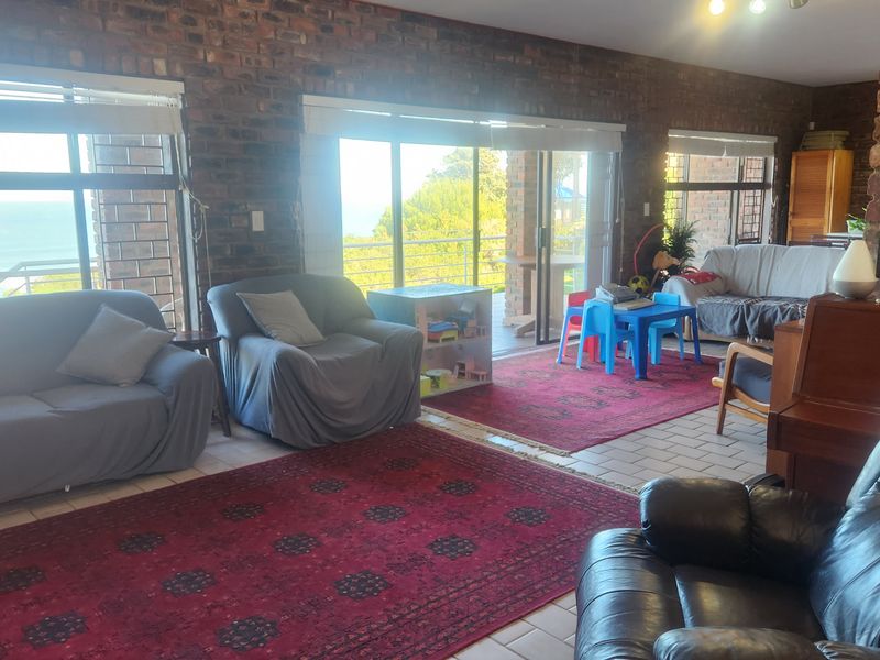 Spacious living room featuring exposed brick walls, a brick fireplace, and large sliding glass doors that provide natural light and access to the outdoors.