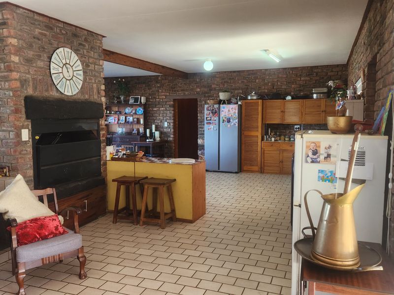 Open-plan living and kitchen area featuring exposed brick walls, a built-in fireplace, and tiled flooring throughout.