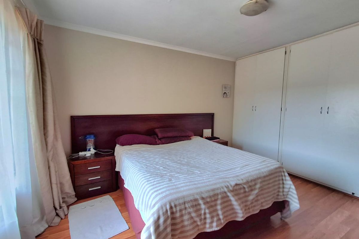 A functional bedroom featuring laminate flooring, neutral wall tones, and ample built-in cupboard storage space.