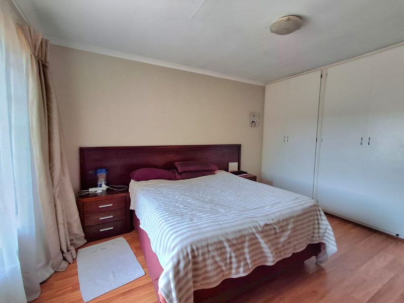 A functional bedroom featuring laminate flooring, neutral wall tones, and ample built-in cupboard storage space.
