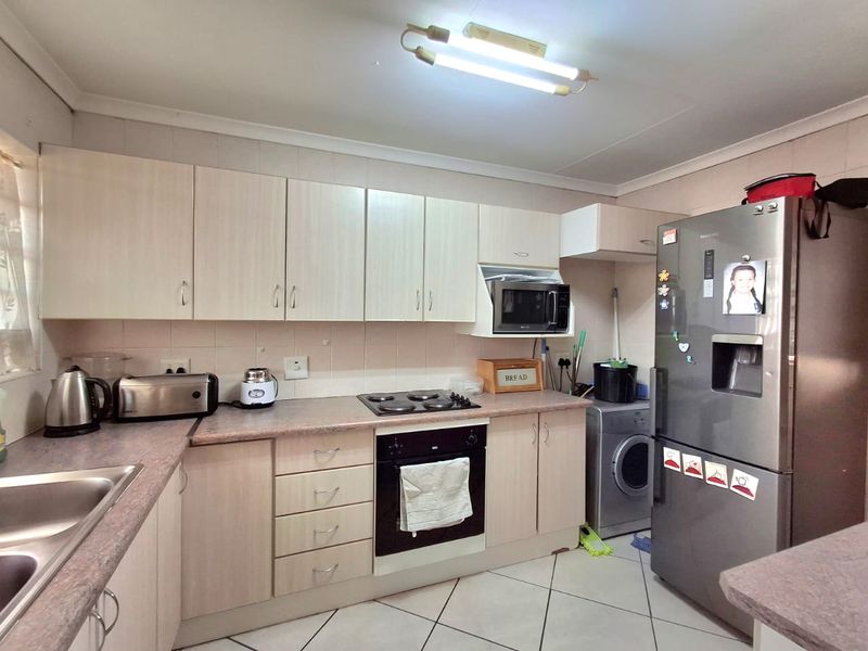 Functional kitchen featuring light-toned laminate cabinetry, built-in oven and hob, tiled backsplash, and tiled flooring, providing a practical workspace for daily meal preparation.