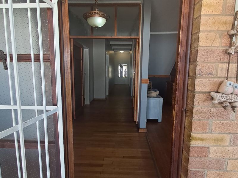An entry hallway featuring timber flooring, a security gate, and a classic pendant light fixture, leading into the main living areas of the home.