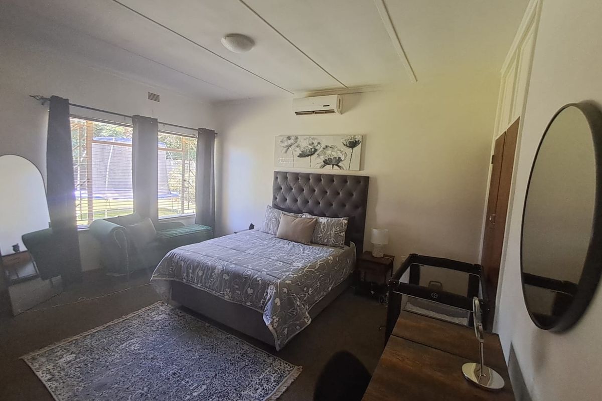 A spacious bedroom featuring a split-system air conditioner, built-in wardrobe, and large windows allowing for natural light.
