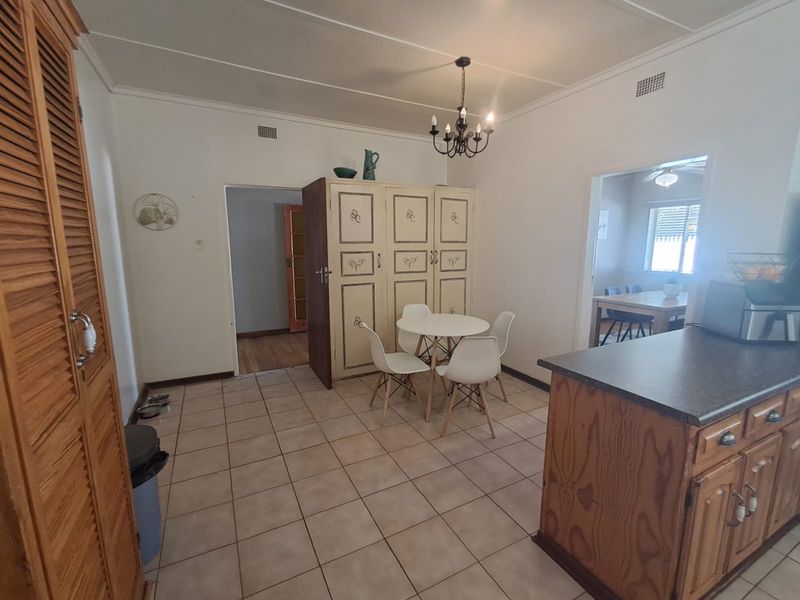 Open plan kitchen and dining area featuring tiled flooring, built-in cabinetry, and a central kitchen island, providing a functional layout for daily living.