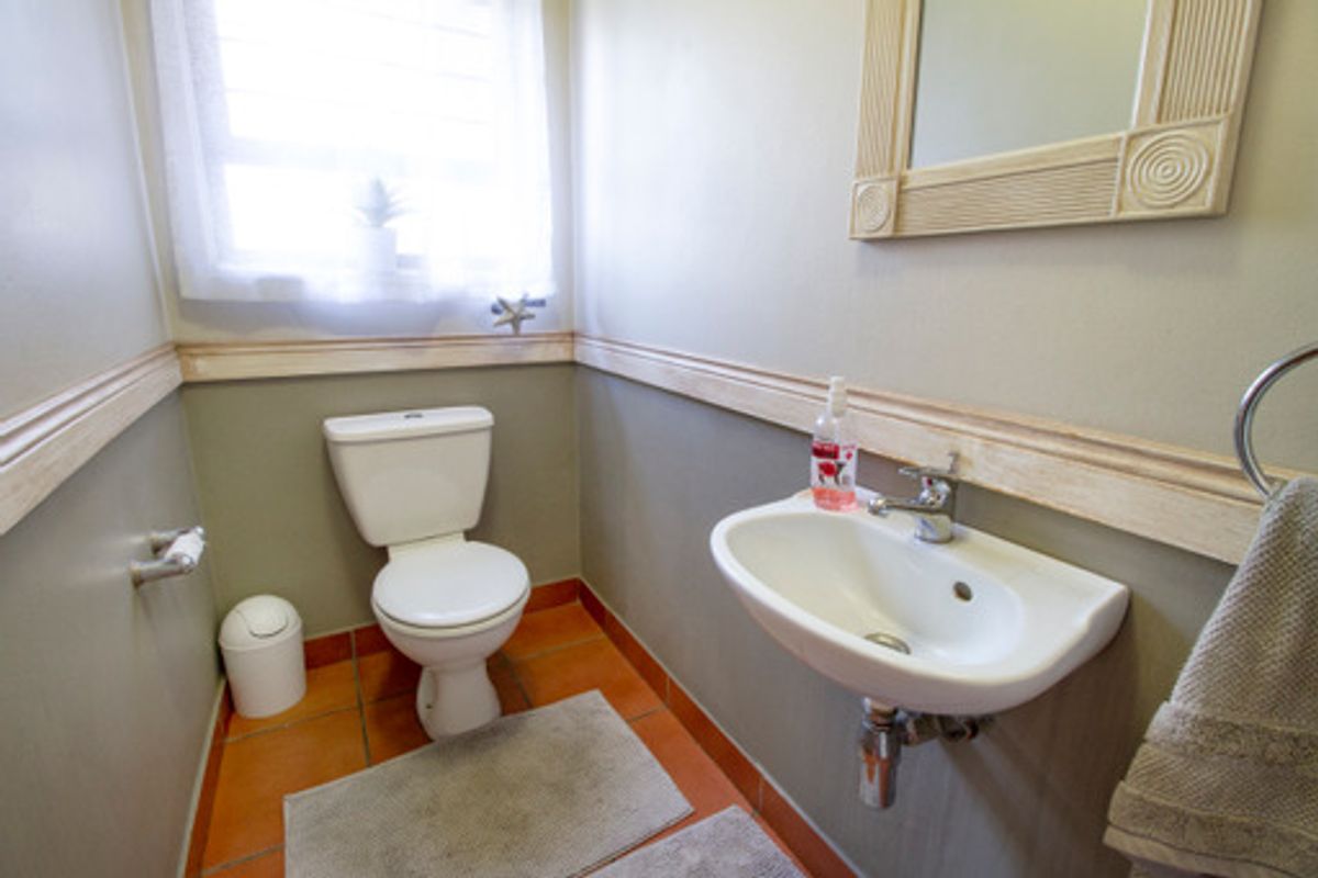 A compact guest bathroom featuring a wall-mounted basin, toilet, and neutral wall finishes with decorative chair rail molding.