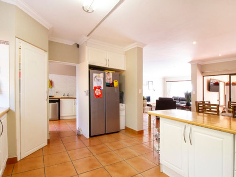 Open-plan kitchen area featuring tiled flooring, built-in cabinetry, and a central island, flowing into the adjacent living and dining spaces.