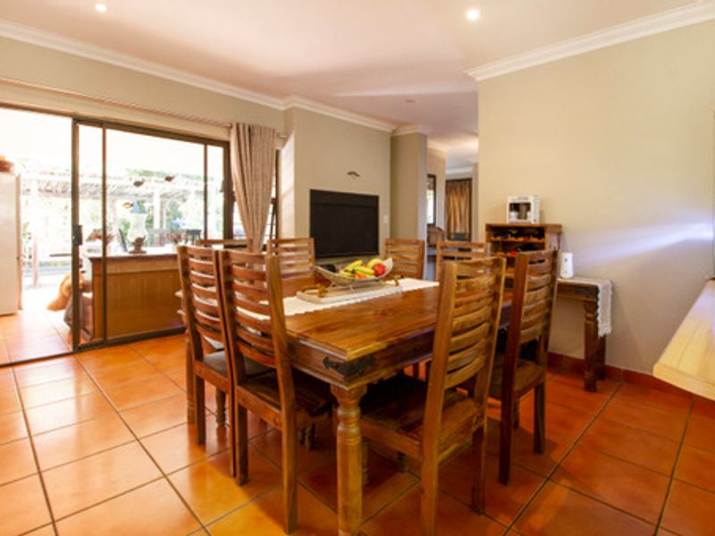 A dining room featuring terracotta floor tiles and large sliding glass doors that provide direct access to the outdoor patio area.