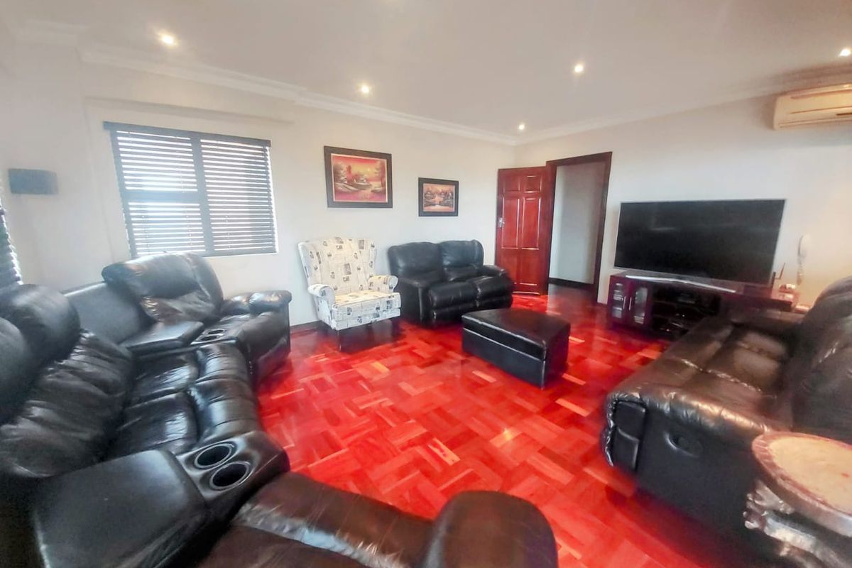 Spacious living room featuring polished parquet flooring, recessed downlighting, and an integrated air conditioning unit, providing a comfortable and well-maintained living space.