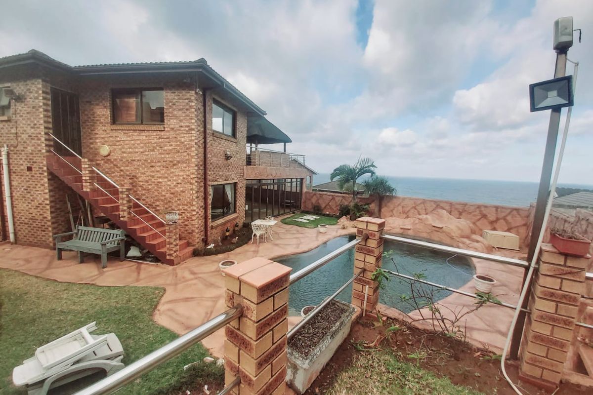 Rear exterior view featuring a swimming pool, paved patio area, brick building facade, and an external staircase with ocean views.