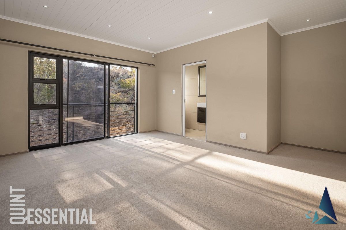 Spacious bedroom featuring neutral carpeting, recessed ceiling lighting, and large sliding glass doors leading to an outdoor balcony with a view.