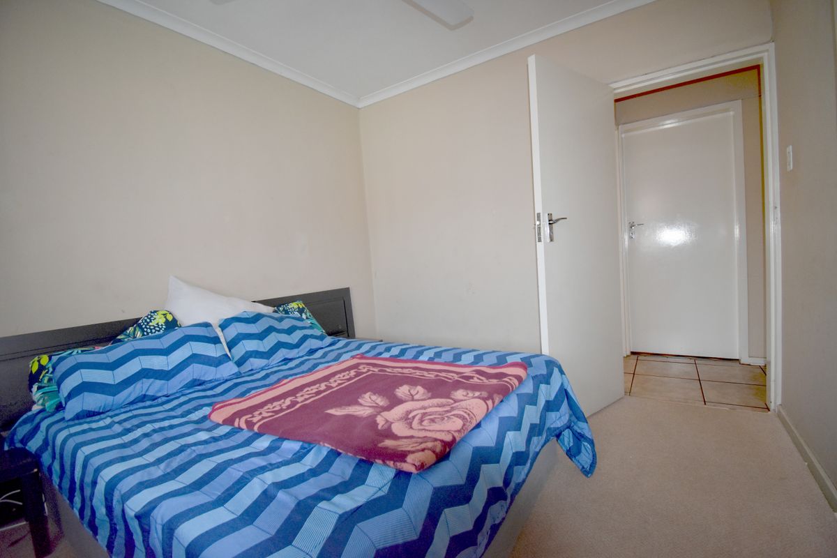 A standard bedroom featuring neutral wall finishes, carpeted flooring, and a doorway leading to an adjacent hallway.