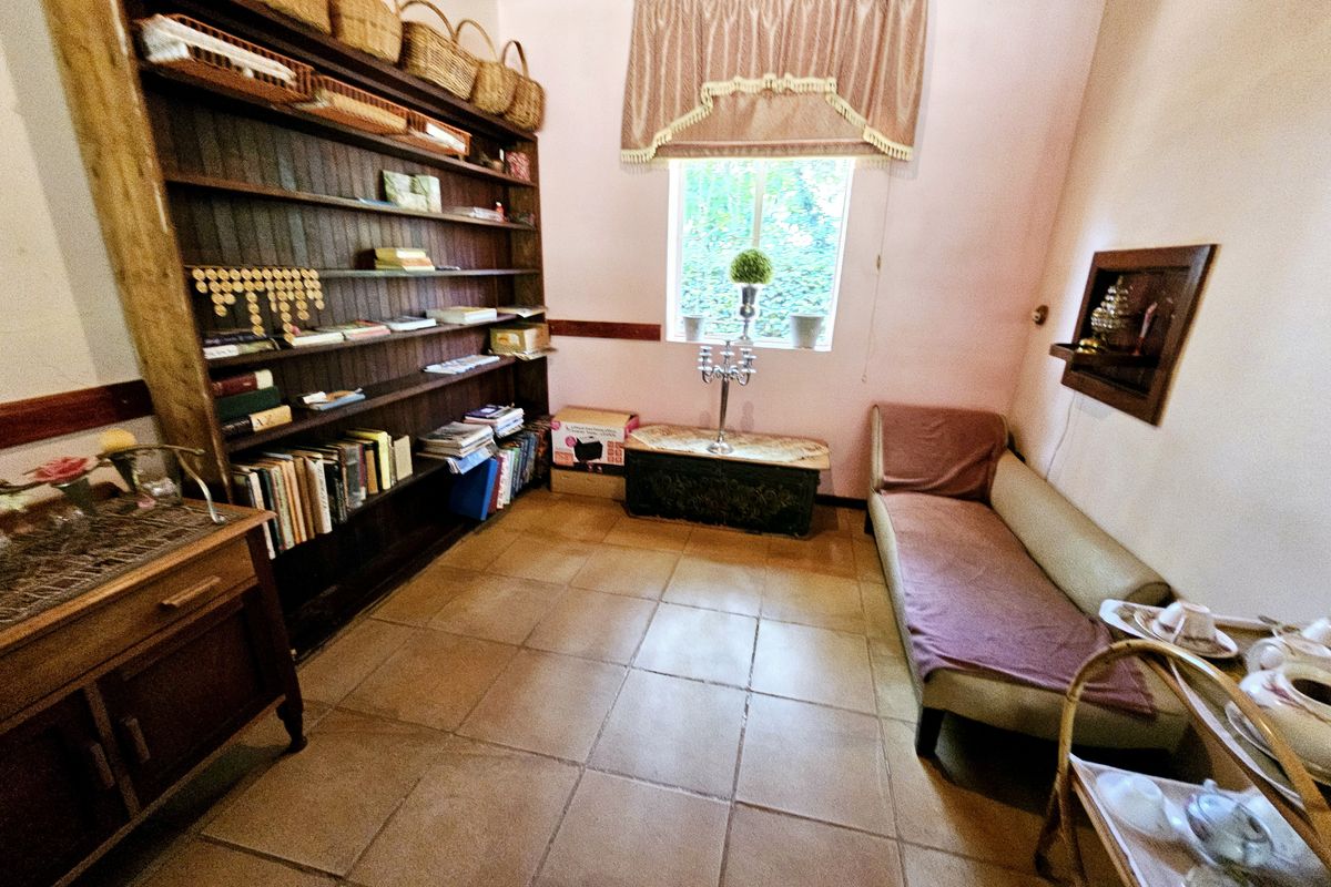 A bedroom featuring tiled flooring, built-in wooden shelving, and a recessed wall niche, offering a functional space with traditional finishes.