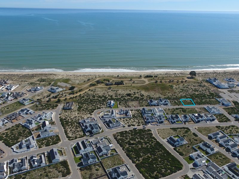 Aerial view of a vacant residential plot situated within a coastal estate, offering proximity to the beach and established neighborhood infrastructure.