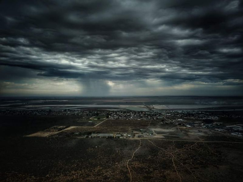 An aerial view of the vacant residential land and surrounding landscape under a dramatic, stormy sky.