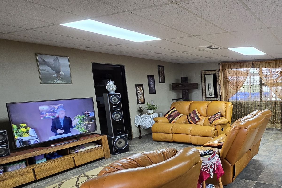 A living room featuring a drop ceiling with recessed lighting and tiled flooring.