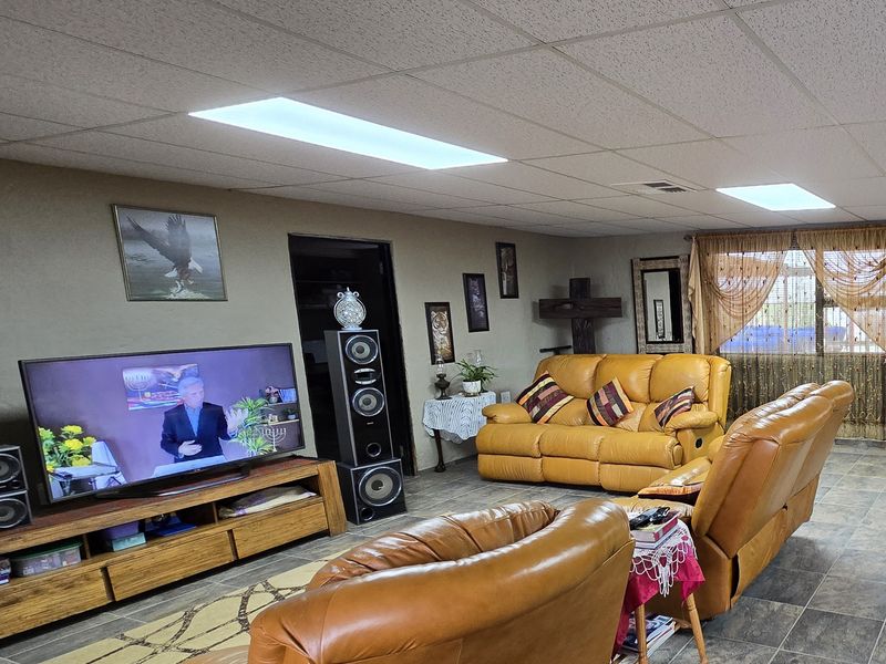 A living room featuring a drop ceiling with recessed lighting and tiled flooring.